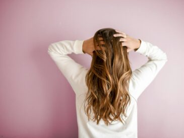 a women standing against wall holding her hair