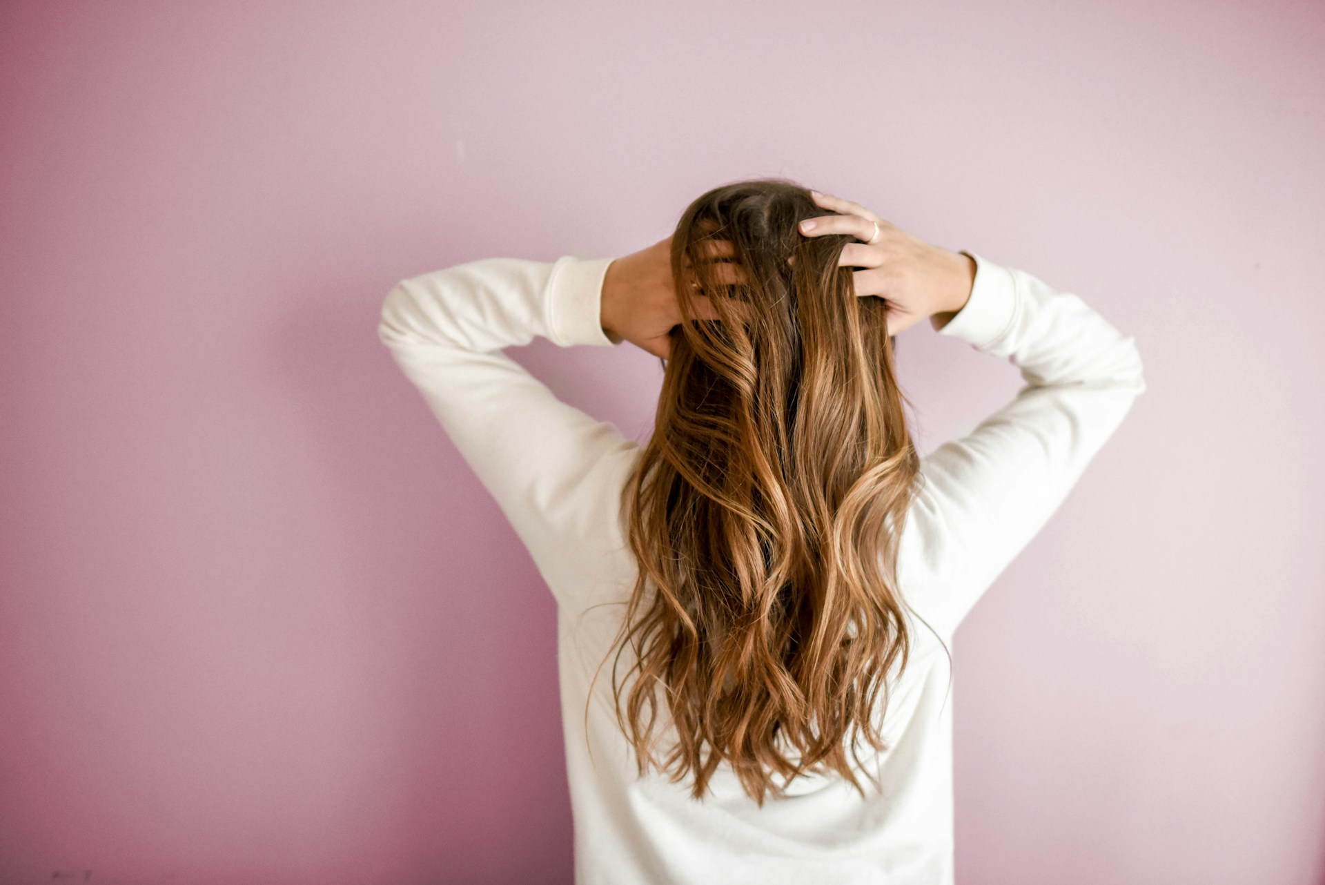 a women standing against wall holding her hair