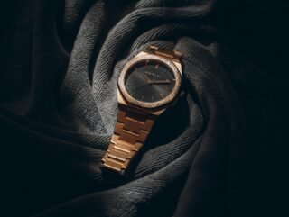 a rose gold watch resting on dark fabric